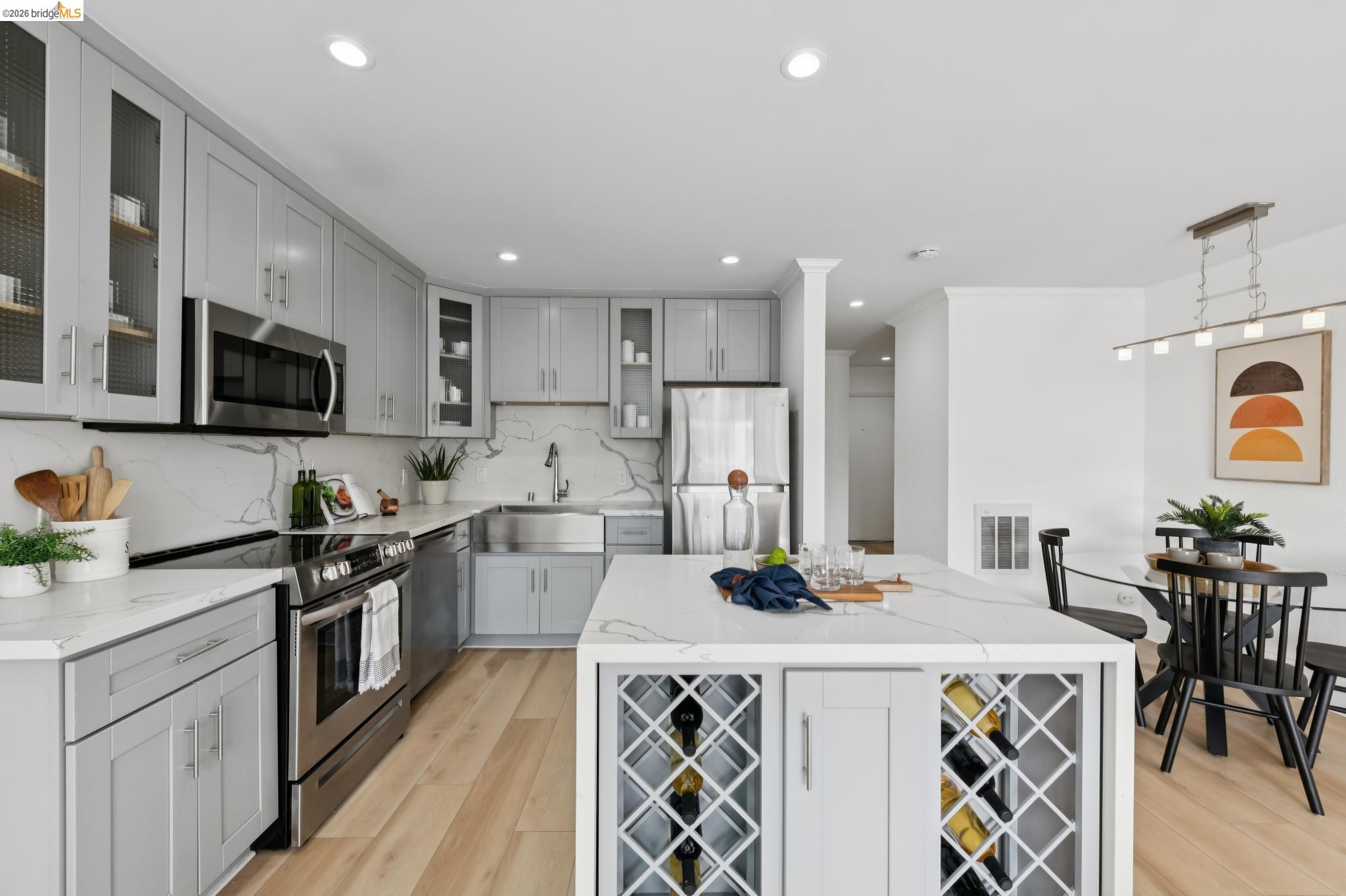 7 Embarcadero, Unit 204 Oakland, CA 94607 - Photo 4 of 27 Kitchen featuring stainless steel appliances, light stone counters, light wood finished floors, a kitchen island, and decorative backsplash