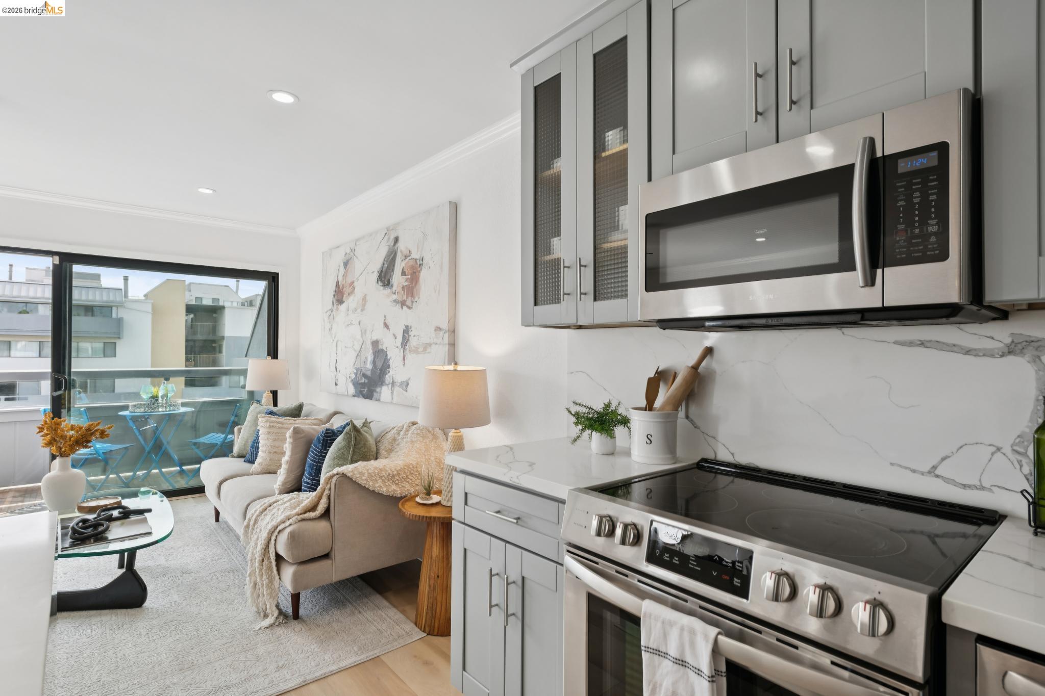 7 Embarcadero, Unit 204 Oakland, CA 94607 - Photo 7 of 27 Kitchen featuring stainless steel appliances, gray cabinets, crown molding, light stone countertops, and backsplash