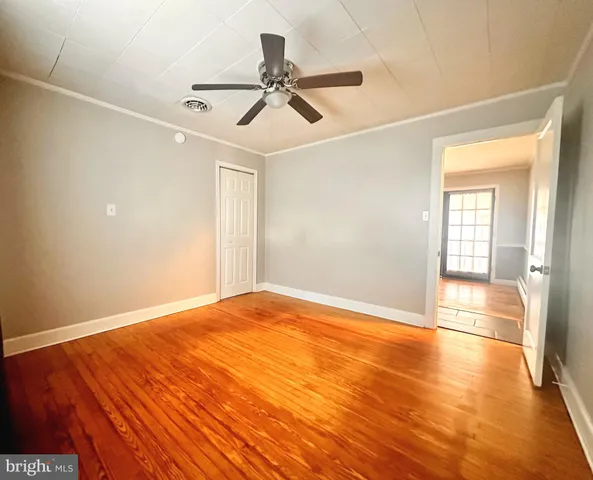 a view of empty room with wooden floor and fan
