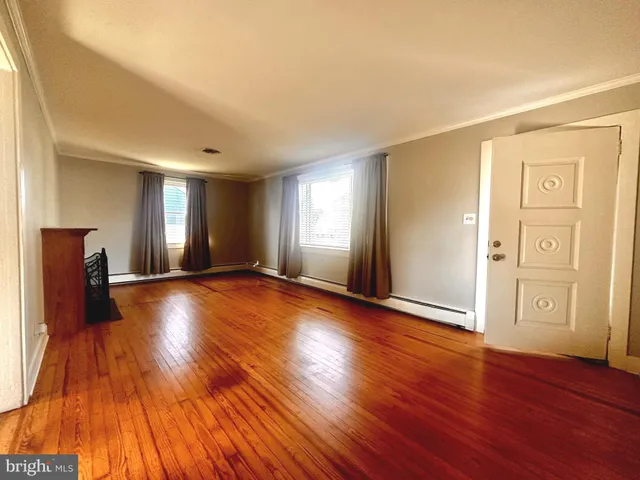 a view of an empty room with window and wooden floor