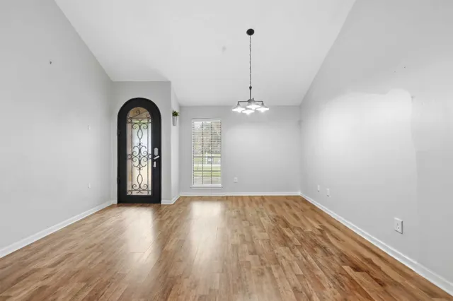 a view of an empty room with window and wooden floor