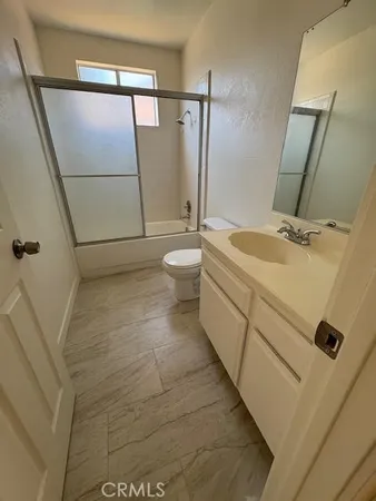 a bathroom with a granite countertop sink a toilet and shower