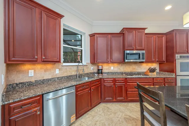 a kitchen with stainless steel appliances granite countertop a refrigerator a stove and a sink