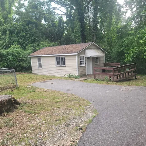 a view of a house with a yard and large tree