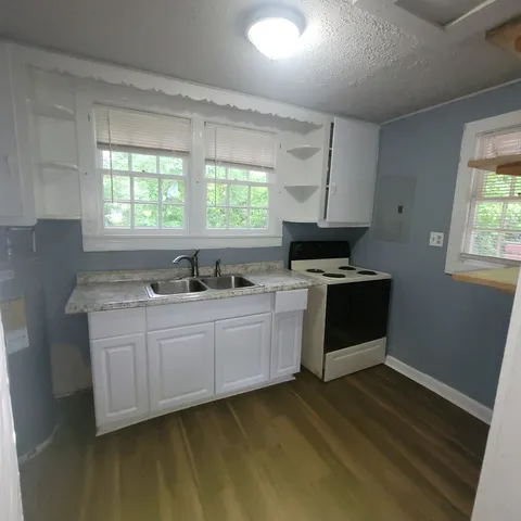 a kitchen with granite countertop a stove a sink and a microwave