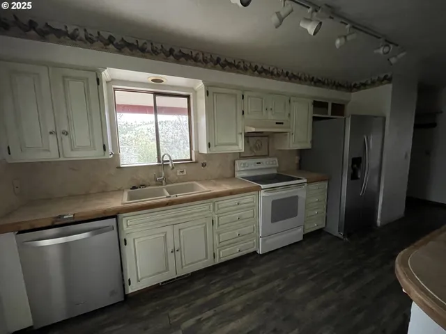 a kitchen that has a sink wooden floor stainless steel appliances and cabinets