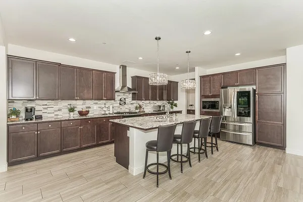 a kitchen with stainless steel appliances kitchen island granite countertop a table chairs sink and cabinets