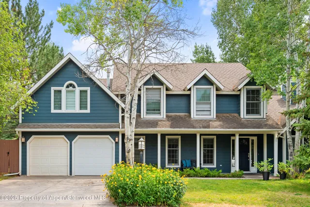 a view of a yard in front of a house with plants and large tree