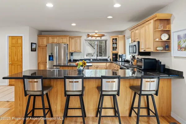 a dining hall with stainless steel appliances granite countertop a dining table and chairs
