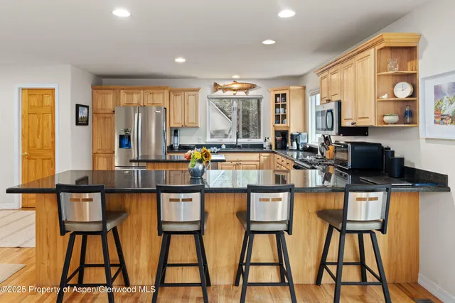 a dining hall with stainless steel appliances granite countertop a dining table and chairs