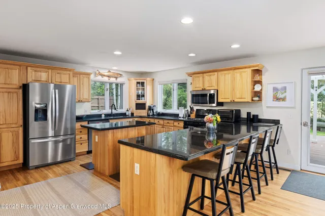 a kitchen with stainless steel appliances granite countertop table chairs refrigerator and microwave