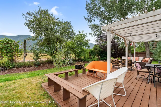 a view of a patio with table and chairs potted plants with wooden floor and fence