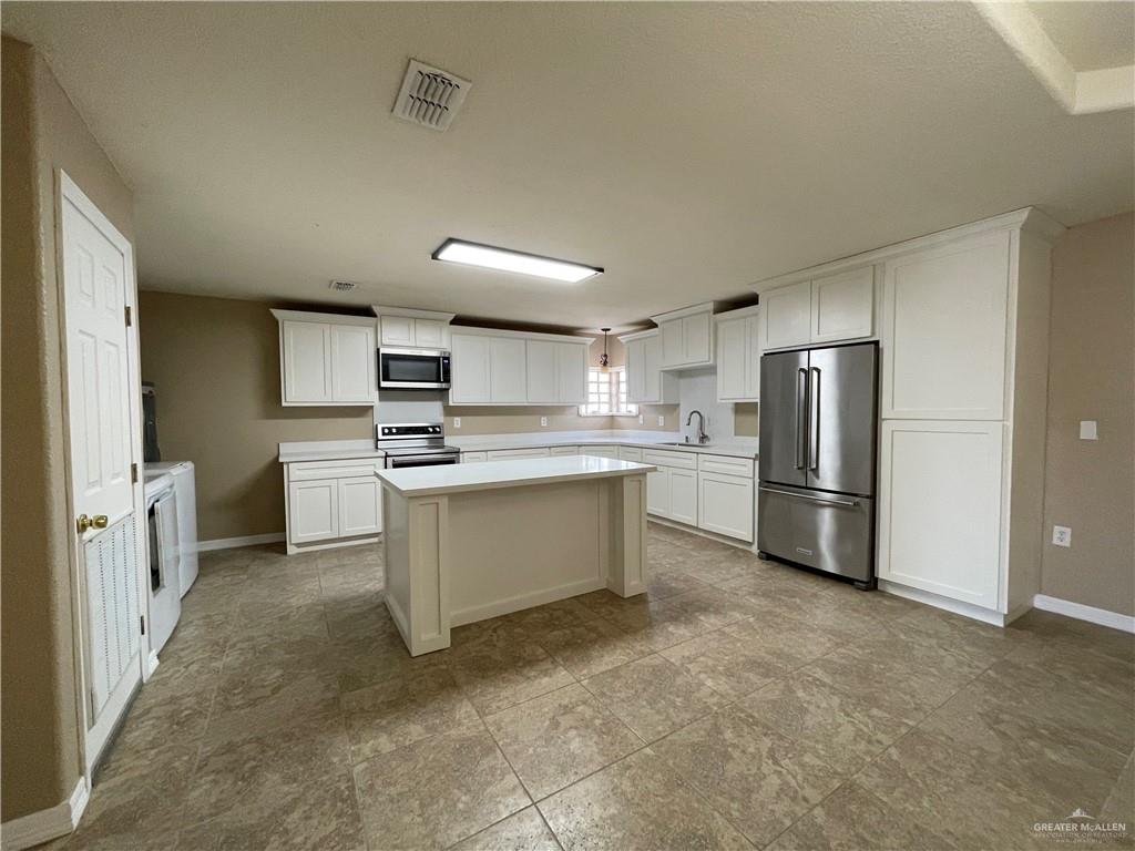 8006 Senecio Street Mission, TX 78574 - Photo 11 of 31 a kitchen with white cabinets and stainless steel appliances