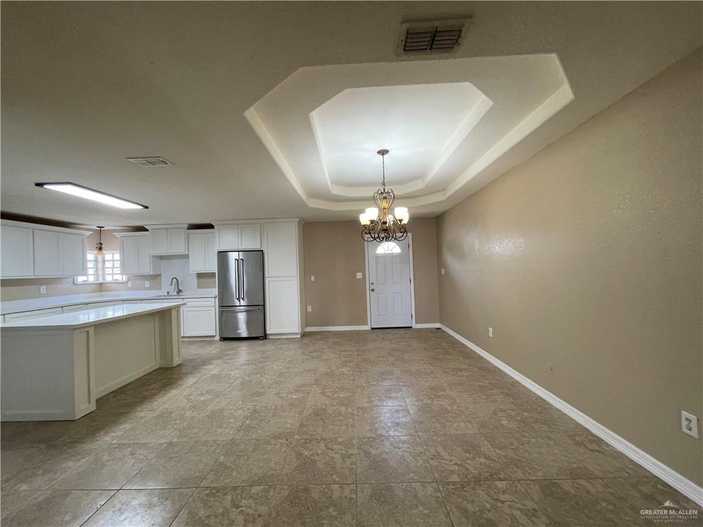 8006 Senecio Street Mission, TX 78574 - Photo 12 of 31 an empty room with kitchen and chandelier fan