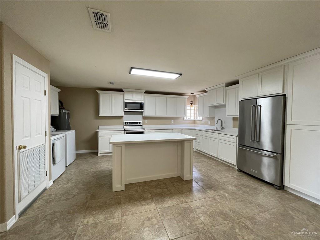 8006 Senecio Street Mission, TX 78574 - Photo 10 of 31 a kitchen with white cabinets and stainless steel appliances