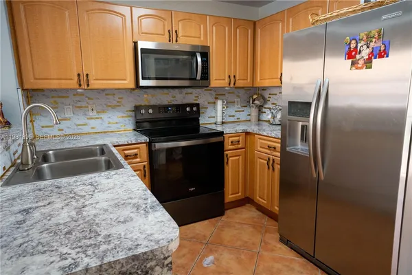 a kitchen with granite countertop a refrigerator stove and microwave