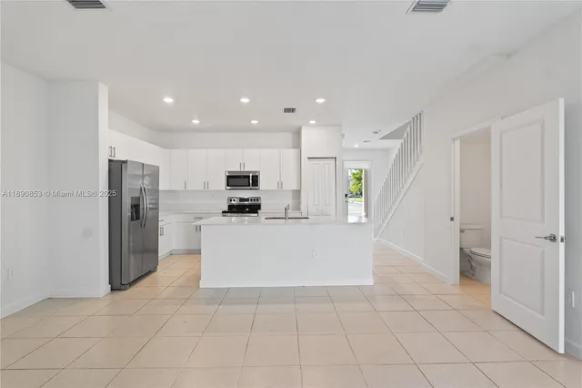 a view of a kitchen with refrigerator and white cabinets