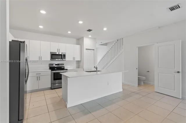 a kitchen with white cabinets and stainless steel appliances