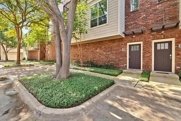 a view of a brick house with a yard and plants