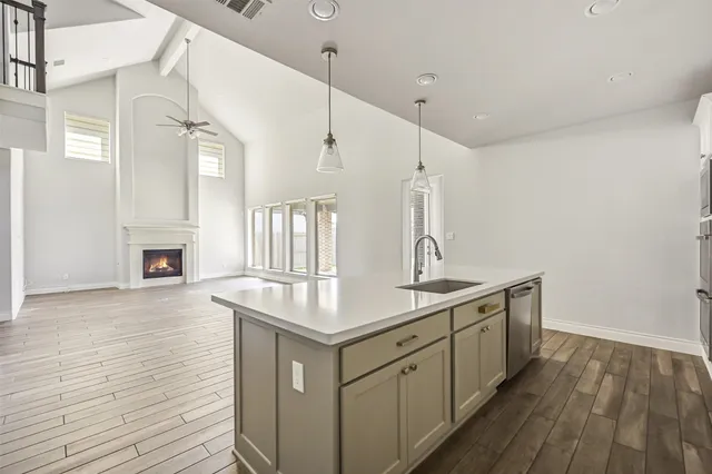 a kitchen with a sink dishwasher a stove and white cabinets with wooden floor