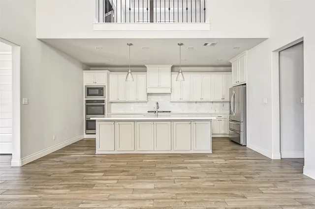 a kitchen with stainless steel appliances cabinets a wooden floor and a window