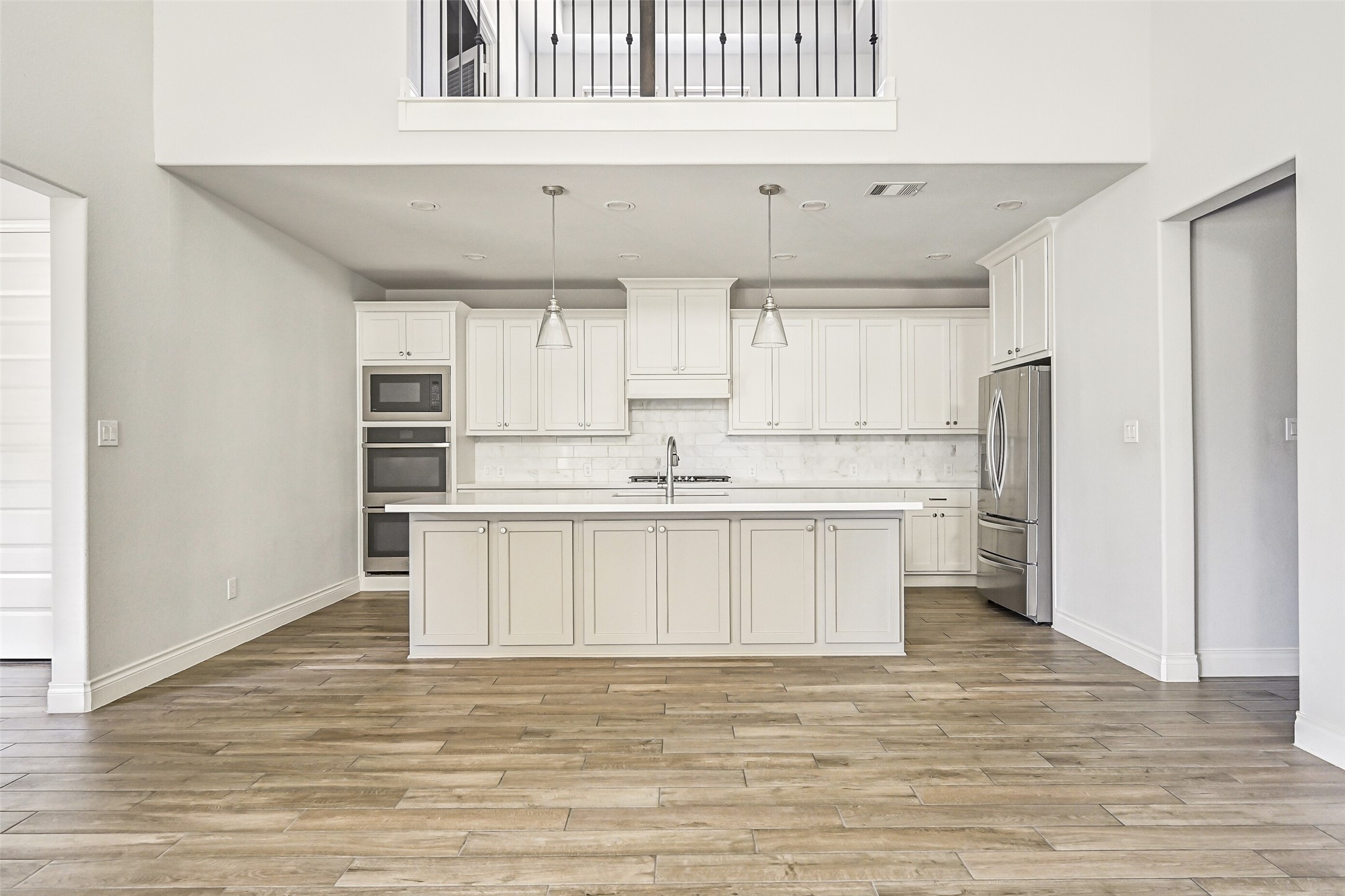 28907 Ridge Valley Court Fulshear, TX 77441 - Photo 7 of 36 a kitchen with stainless steel appliances cabinets a wooden floor and a window