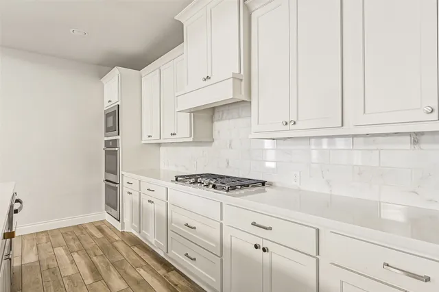 a kitchen with granite countertop white cabinets and stainless steel appliances
