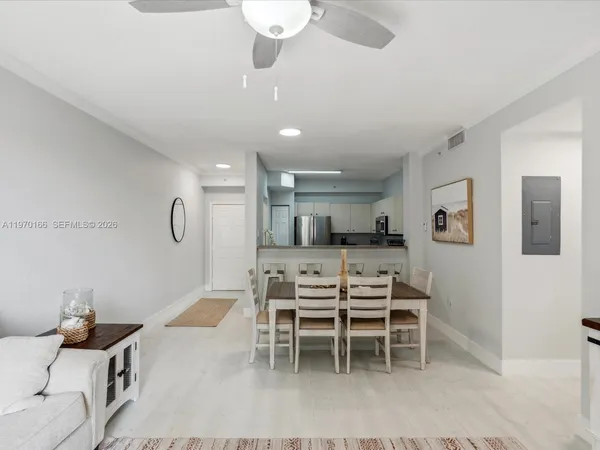 a kitchen with stainless steel appliances kitchen island granite countertop a stove a sink a dining table and chairs with wooden floor