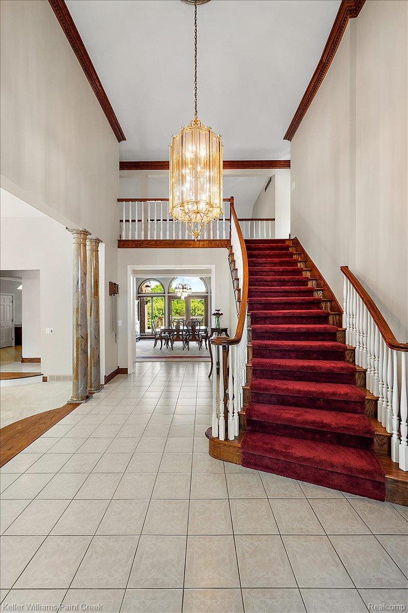 69069 Campground Road Romeo, MI 48065 - Photo 20 of 78 Grand foyer featuring a curved staircase with a red runner, a large decorative chandelier, and light-toned square floor tiling