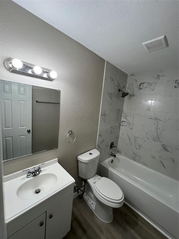 8335 Tenino Street Dallas, TX 75217 - Photo 21 of 22 Bathroom featuring shower combination, vanity, a textured wall, dark wood-style flooring, and a textured ceiling