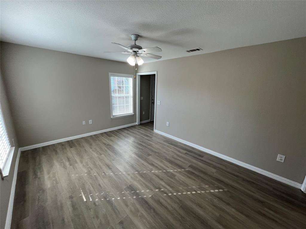 8335 Tenino Street Dallas, TX 75217 - Photo 4 of 22 Unfurnished room with dark wood-style floors, a textured ceiling, and ceiling fan