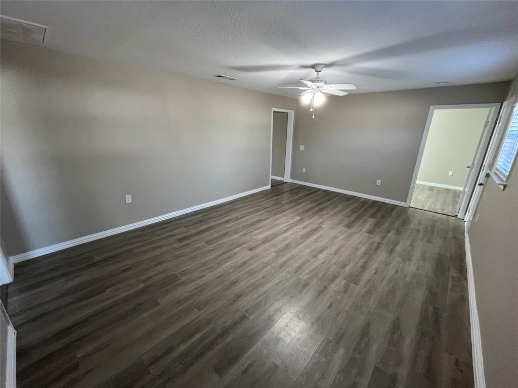 8335 Tenino Street Dallas, TX 75217 - Photo 10 of 22 Empty room with dark wood-type flooring, a ceiling fan, and a textured ceiling