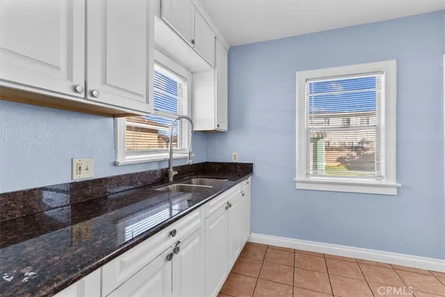 a kitchen with granite countertop white cabinets and sink