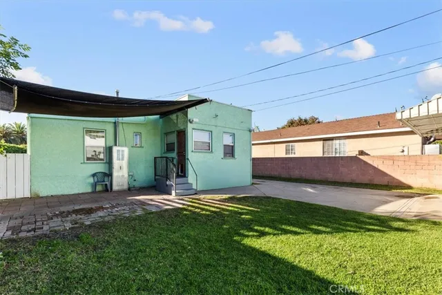 a view of yellow house with a big yard and a large tree