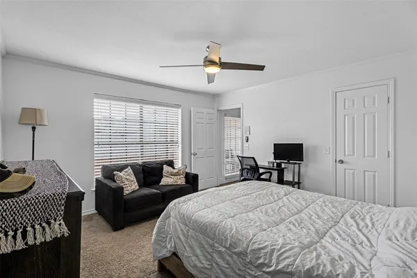 a spacious bedroom with a bed a couch and a dresser with wooden floor