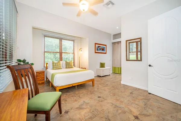 a spacious bedroom with a bed a couch and a dresser with wooden floor