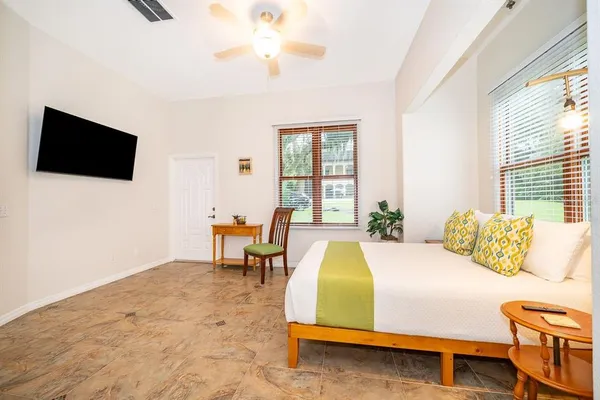 a bedroom with a bed a flat screen tv and a large window