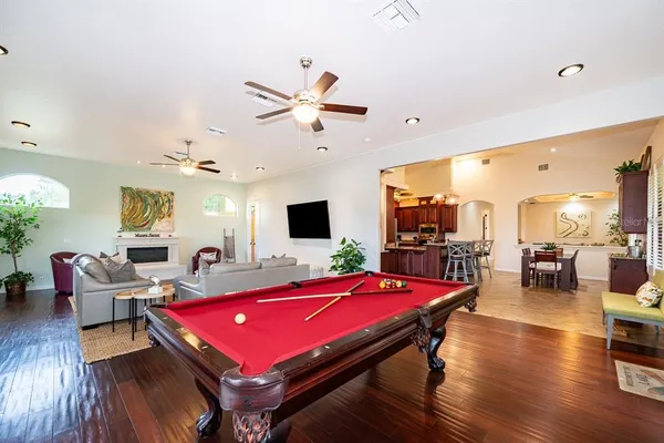 a room with furniture pool table wooden floor and windows