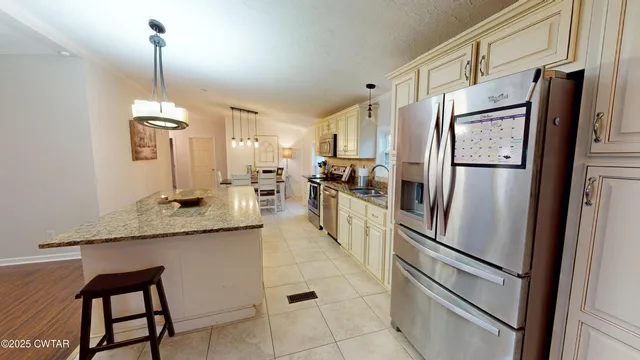 a kitchen with granite countertop white cabinets and chandelier