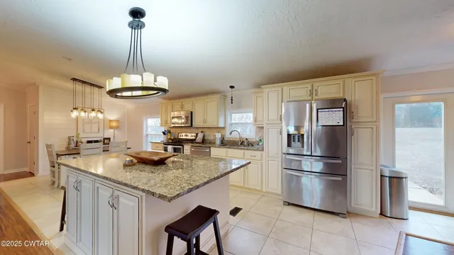 a kitchen with stainless steel appliances granite countertop a sink a refrigerator and a wooden floor