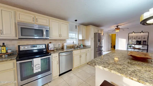a kitchen with granite countertop a stove sink and refrigerator