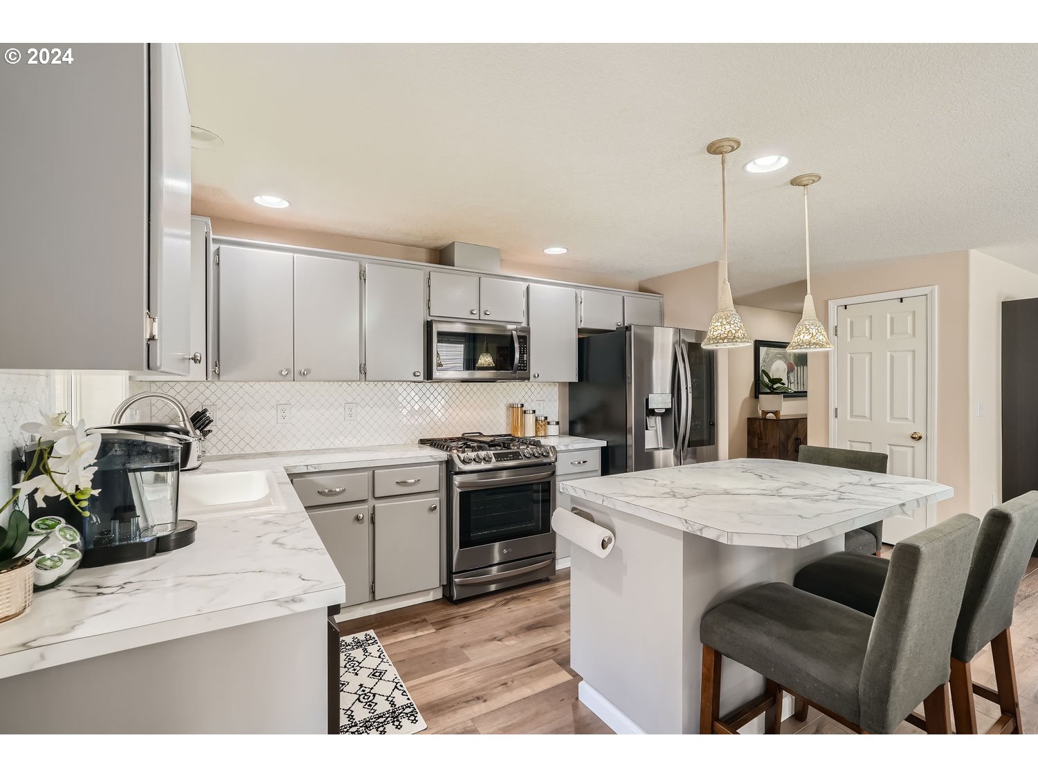 19504 Southeast 41st Circle Camas, WA 98607 - Photo 10 of 27 a kitchen with stainless steel appliances kitchen island granite countertop a stove top oven a sink refrigerator and white cabinets