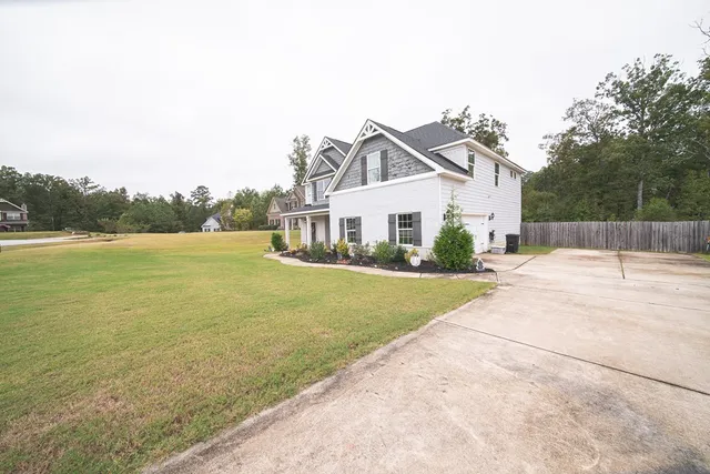 a front view of a house with a yard and lake view