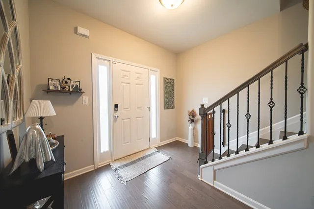 a view of front door with hallway and wooden floor