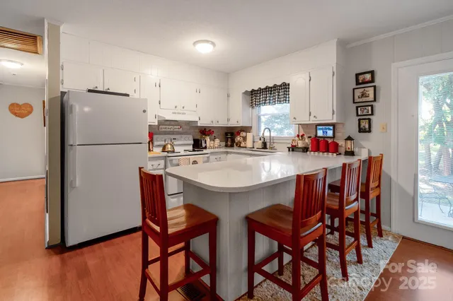 a kitchen with stainless steel appliances a white table chairs and a refrigerator
