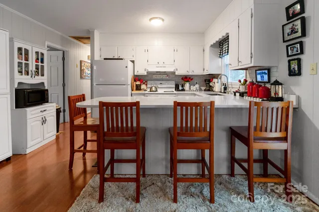 a kitchen with stainless steel appliances granite countertop a dining table chairs and a refrigerator