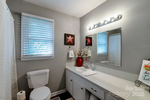 a bathroom with a granite countertop toilet sink and mirror