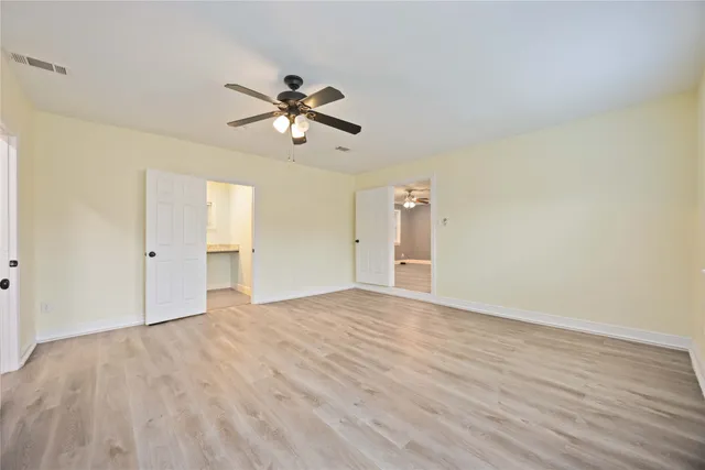 a view of empty room with wooden floor and ceiling fan