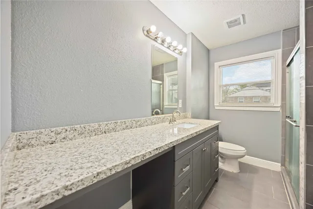 a bathroom with a granite countertop sink a toilet and a large mirror