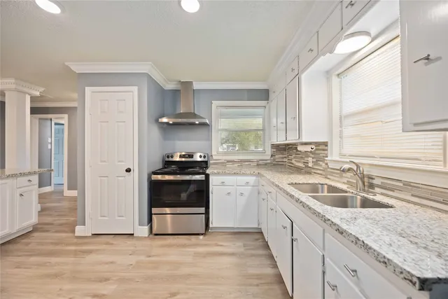 a kitchen with a sink dishwasher a stove and white cabinets with wooden floor